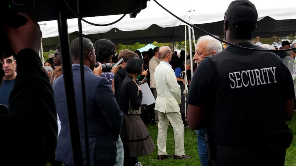 security guard watching over a crowd of people from under a tent