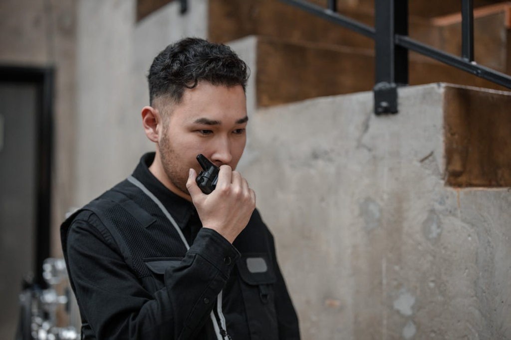 A photo showing a man speaking into a walkie talkie.